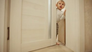 Küçük çocuk pijama evde iken gizle oynamak ve kapı ile aramak. Açılır ve odasının kapısını kapatır. Yakın çekim.