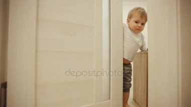 Küçük çocuk pijama evde iken gizle oynamak ve kapı ile aramak. Açılır ve odasının kapısını kapatır. Yakın çekim.