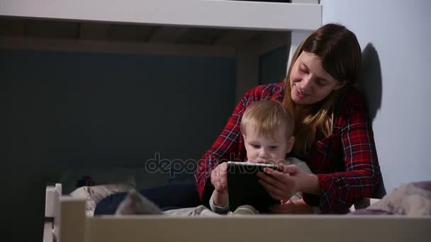 Yakın çekim shot, oğlu ve annenin üzerinde oyun oynama yatakta dokunmatik yüzey. Uyku zamanı eğlence. — Stok video