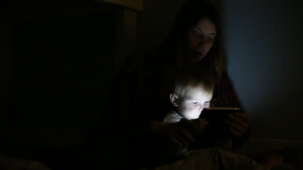 Close-up shot syna a matky v posteli hrát hry na dotykový displej. Před spaním zábava. — Stock video