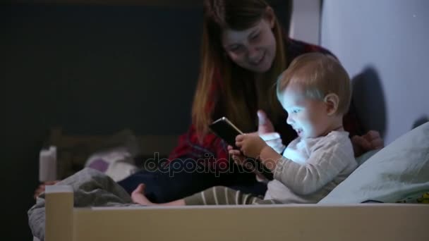 Close-up shot of son and mother in bed playing game on touch pad. Bedtime entertainment. — Stock Video