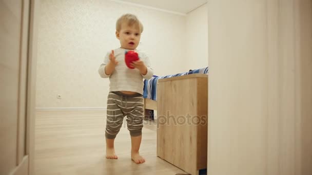 Menino de pijama em casa a brincar às escondidas com a porta. Abre e fecha a porta do quarto. Close-up . — Vídeo de Stock