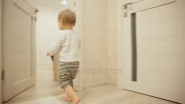 Mały chłopiec w piżamie w domu Gry w chowanego z drzwi. Otwiera i zamyka drzwi do pokoju. Szczelnie-do góry. — Wideo stockowe