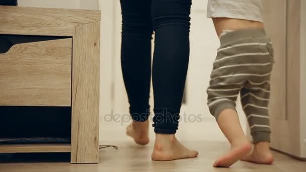 Primer plano de los pies de la madre y el bebé dando los primeros pasos alrededor de la casa. Pies subiendo las escaleras . — Vídeos de Stock