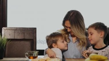 Sarılma ve onların çocukları mutfakta kahvaltı için öpüşme anne. Çocuklar gülüyor.