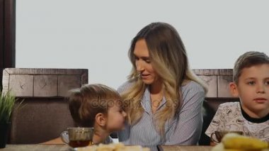 Sarılma ve onların çocukları mutfakta kahvaltı için öpüşme anne. Çocuklar gülüyor.