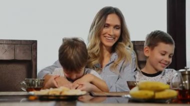 Sarılma ve onların çocukları mutfakta kahvaltı için öpüşme anne. Çocuklar gülüyor.