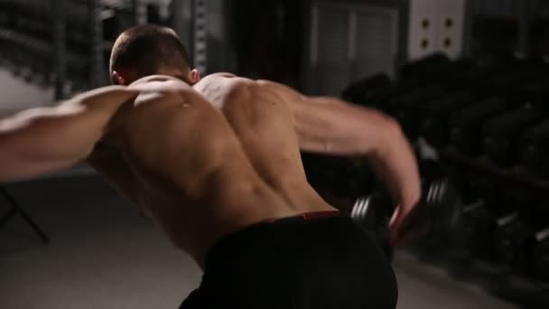 波打つジムでダンベルで肩の運動を行う筋肉を持つ男を延. — ストック動画