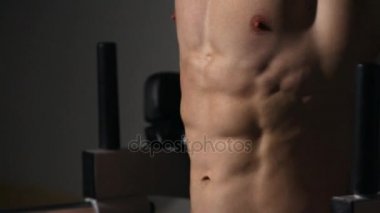 spor salonunda yatay çubuğu'nda bir adamla bacak ile çıplak gövde mekik yükseltir.