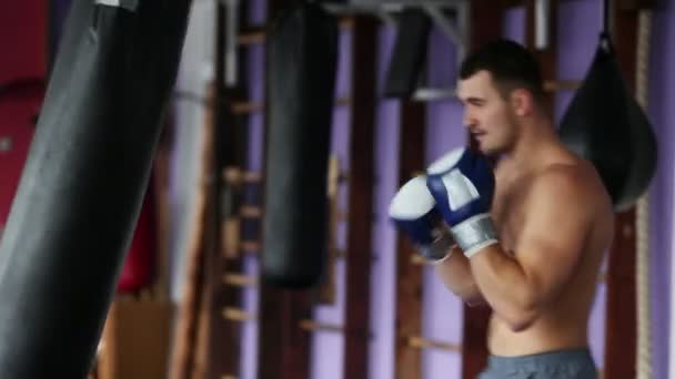 肌肉男职业拳击手训练在拳击手套在健身房打沙袋裸露胸部. — 图库视频影像