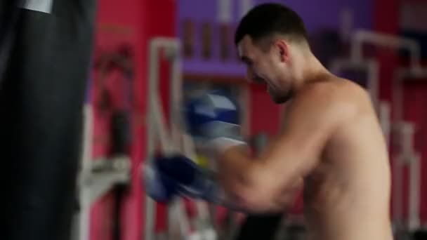Un boxer profesionist efectuează greve pe punga de perforare cu mănuși de box goale. O mişcare verticală a camerei în apropiere. Pan. Picioarele boxerului . — Videoclip de stoc