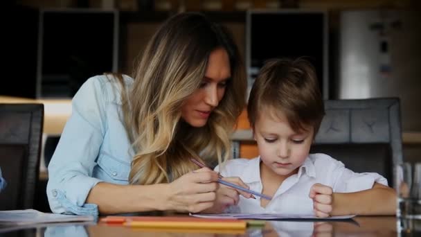 Mooie moeder helpt haar zoon om te schilderen met kleurpotloden beeld. Bij het ontwikkelen van de verbeelding van een childs. — Stockvideo