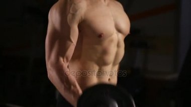 Atletik gömleksiz genç spor adamı - fitness modeli halter salonunda tutar. Yakın çekim