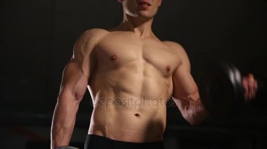 Atletik gömleksiz genç spor adamı - fitness modeli halter salonunda tutar. Yakın çekim