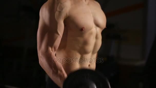 Jeune homme sportif sans chemise athlétique modèle de remise en forme tient l'haltère dans la salle de gym. Gros plan — Video