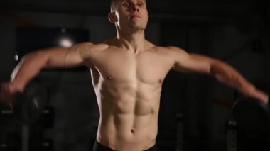 Spor salonunda dumbbells ile omuz egzersizleri performans kasları dalgalanan ile adam haddelenmiş.