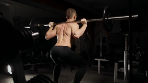 Guapo musculoso hombre ejercicio sentadillas en el gimnasio . — Vídeos de Stock