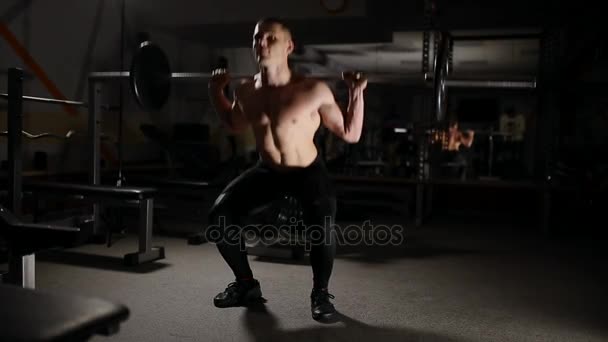 Knappe gespierde man oefening kniebuigingen in de sportschool. — Stockvideo