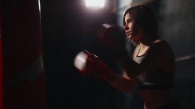 Sportif esmer boks jimnastik salonu stroke tekniği üzerinde bireysel eğitim sağlar. Yürüten grev kum torbasına siyah bir arka plan üzerinde.