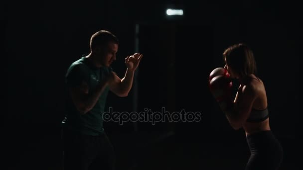 Dívka svalová fitness trénink s jeho instruktor provádět údery na nohy v Boxerské rukavice. Lekce sebeobrany. Trénink boxu. — Stock video