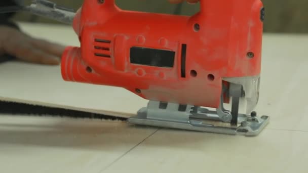 Close-up, in the mans hand electric jig saw sawing a piece of plywood. — Stock Video