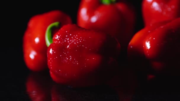 Fresh red peppers freshly washed drops flow down on the table. Closeup rotating on black background. — Stock Video