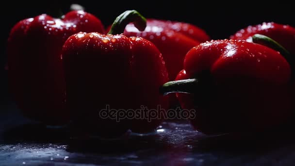 Fresh red peppers freshly washed drops flow down on the table. Closeup rotating on black background. — Stock Video