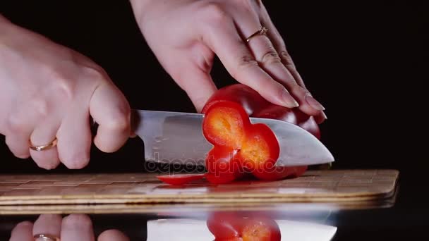 Reife rote Paprika weibliche Hände Nahaufnahme schneidet auf einem Schneidbrett mit einem Messer. — Stockvideo