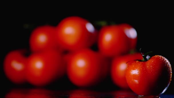 Čerstvé umyté rajčata jsou na povrchu na černém pozadí. Detail z kapky vody teče po povrchu zeleniny. — Stock video