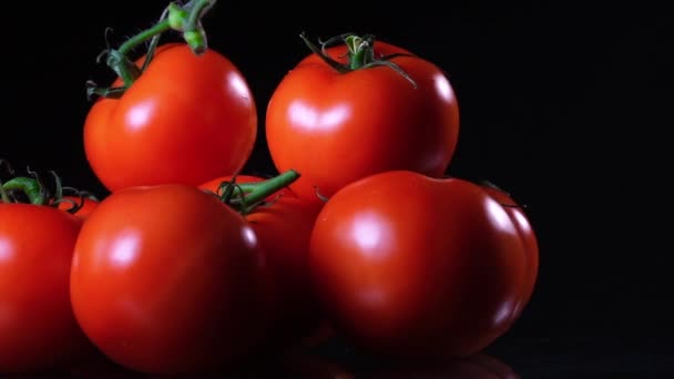 Beaucoup de tomate fraîche mûre couchée sur une table en verre noir et tourne autour de son axe. Gros plan légumes frais . — Video