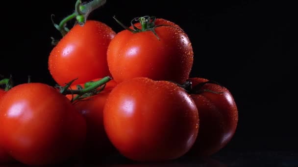 A lot of ripe fresh tomato lying on a black glass table and rotates around its axis. Close-up fresh vegetables. — Stock Video