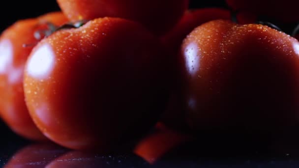 Beaucoup de tomate fraîche mûre couchée sur une table en verre noir et tourne autour de son axe. Gros plan légumes frais . — Video