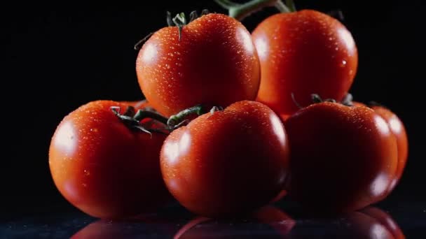 A lot of ripe fresh tomato lying on a black glass table and rotates around its axis. Close-up fresh vegetables. — Stock Video