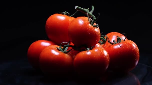 Una gran cantidad de tomate fresco maduro acostado en una mesa de vidrio negro y gira alrededor de su eje. Primer plano verduras frescas . — Vídeo de stock