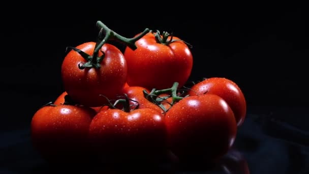 Beaucoup de tomate fraîche mûre couchée sur une table en verre noir et tourne autour de son axe. Gros plan légumes frais . — Video