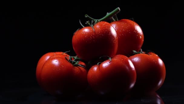 Een heleboel rijpe verse tomaat, liggend op een zwart glazen tafel en rond zijn as draait. Close-up verse groenten. — Stockvideo