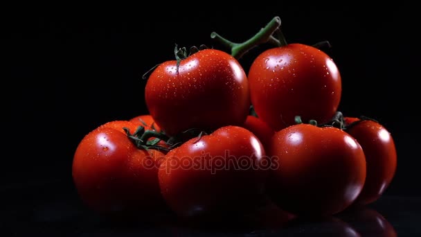 Багато стиглих свіжих помідорів лежать на чорному скляному столі і обертаються навколо його осі. Крупним планом свіжі овочі . — стокове відео
