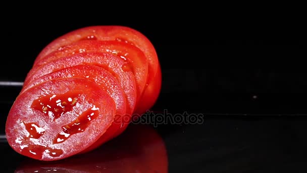 검은 배경에 검은 테이블에 회전 칼 함께 익은 토마토를 슬라이스. — 비디오
