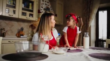 Anne ve kızı kırmızı önlük mutfakta bir defter tarifi pasta okuyun.