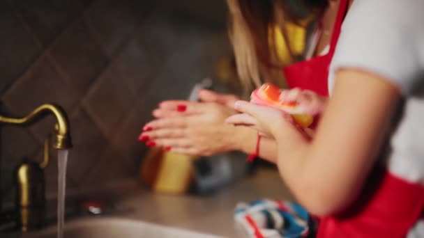 Mamá ayuda a lavarse las manos de su hija en la cocina después de cocinar la cena . — Vídeo de stock