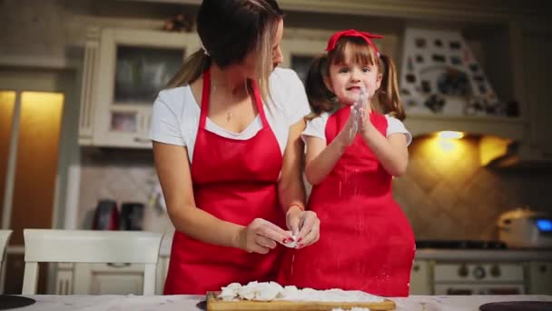 Ευτυχισμένη οικογένεια στην κουζίνα μαμά και κόρη στην κουζίνα παίζει με αλεύρι για να διασκεδάσουν και να πλάθουμε τα μπιφτέκια στην κουζίνα σε το ίδιο κόκκινες ποδιές. stedicam — Αρχείο Βίντεο