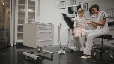 Küçük bir kız diş telleri yükledikten sonra diş fırçalamayı öğrenme x-ray başkanı arka plan üzerinde diş hekimleri office ortodontist. Diş hekimi diş Temizleme için bir Danışma yürütmektedir.