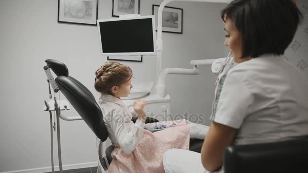 Dokter gigi Childrens melakukan konsultasi dengan gadis kecil di kantorku. Dokter berbicara dengan seorang gadis membahas pengobatan di masa depan . — Stok Video