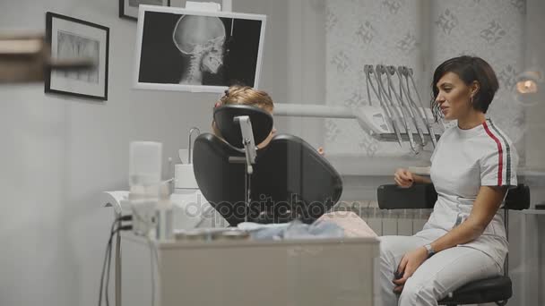 Il dentista infantile conduce un consulto con la bambina nel mio studio. Il dottore parla con una ragazza che sta discutendo di un trattamento futuro . — Video Stock