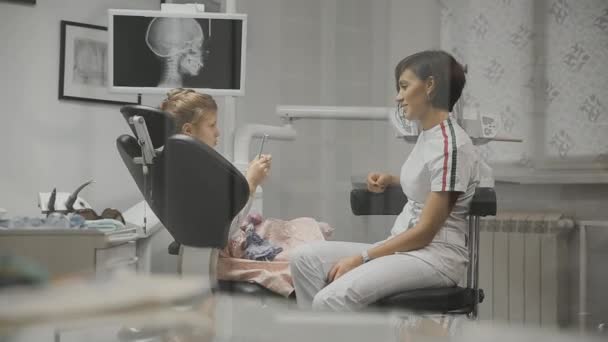 儿童牙医与我办公室的小女孩进行会诊。医生和一个女孩谈论未来的治疗. — 图库视频影像