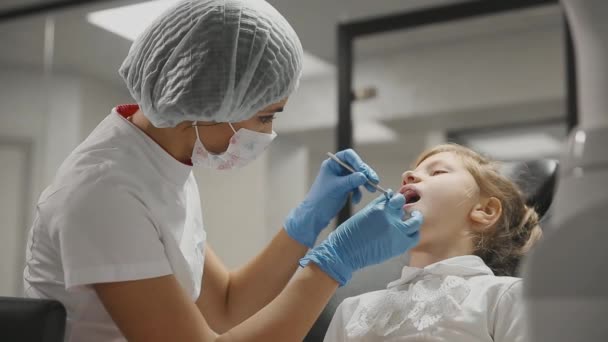 Dentysta bada nawiasy klamrowe małą dziewczynką i sprawdza na obecność próchnicy zębów. Biurze Dentyści. — Wideo stockowe