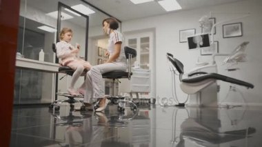 Dişçi kız diş fırçalama anlatır. Doğru fırçalama olarak gösteriyor. Kamera isabet. Kamera zoom.