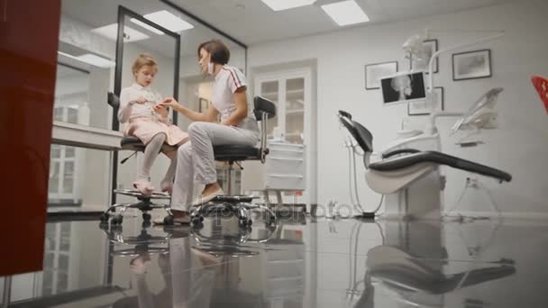 The dentist tells the girl how to brush teeth. Shows the layout as brushing correctly. Hitting the camera. Zoom camera. — Stock Video