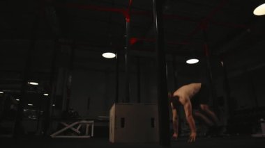 Kaslı adam gömleksiz burpee egzersiz ve atlama kadar bir tahta üzerinde gerçekleştirir
