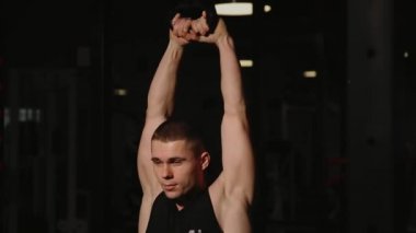 Kaslı adam spor salonunda ağırlık egzersizleri yapıyor. Kettlebell parçalarının.